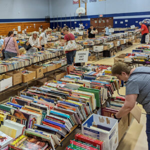 A school gym full of tables covered with used books for sale